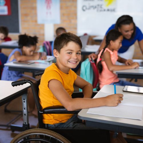 A boy in a wheelchair smiling while in class